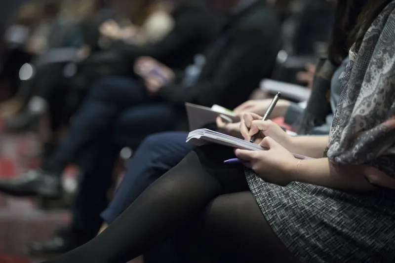 People seated at a meeting taking notes