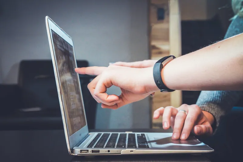Hand pointing at a laptop screen